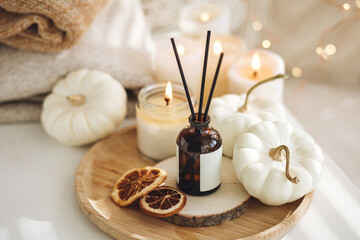 Still life details in the living room. Autumn composition with aroma diffuser with pumpkin pie scent, knitted sweaters, burning candles. Concept of slow life, relaxation, detention. Apartment decor - obrazy, fototapety, plakaty