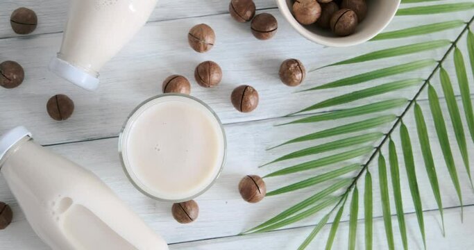 macadamia milk on table, vegan drink served on table, alternative milk bottles, slow motion video, close-up video, top table view. High quality 4k footage