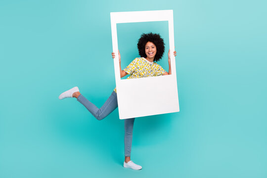 Full length photo of cheerful optimistic girl wear trendy outfit have fun hold photography peek out hole isolated on cyan color background