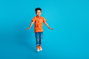 Full body cadre of good mood funky positive boy small jump trampoline air active free time spending isolated on blue color background