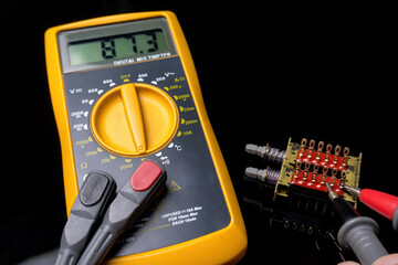 Electronics, close-up of a digital multimeter with its tips measuring the status of a combination...