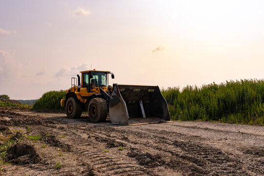 Yellow bulldozer - parked on dirt road - rural area with field and trees. Taken in Toronto, Canada.