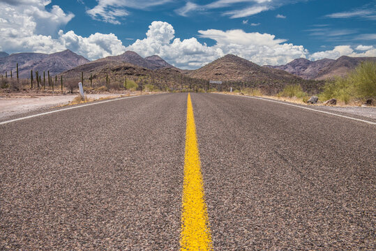 Road from Loreto to Santa Rosalia in the Baja desert in Mexico, with mountains and clouds mixed with blue sky in the backgroun. Landscape of the beautiful Baja