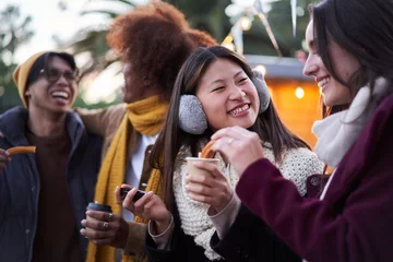 Foto op Aluminium Happy smiling friends eating chocolate with churros together on the street outdoors. Tour group of four multiracial people gathered having fun at festival in winter. Persons holding cup of hot drink.  © CarlosBarquero