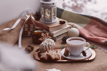 Cozy aesthetic Christmas window with homemade gingerbread cookies, walnuts, marshmallow, cup of cocoa, candles cozy background