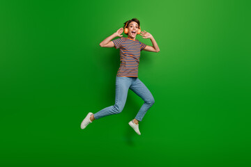 Fototapeta na wymiar Full body photo of pretty overjoyed astonished lady jumping listen favorite song isolated on green color background
