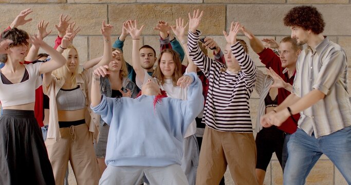 Dance master class at summer camp. Portrait of Young girl shows dance moves to group of students, active hand gestures. Foster a sense of community and camaraderie among dancers. Lifestyle people.