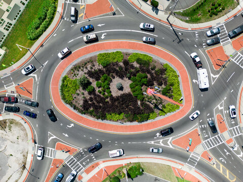 Aerial view of typical urban traffic circle with vehicles seen from overhead.
