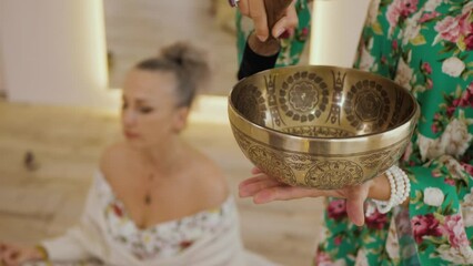 Vibration from a Tibetan bowl, blurred copy space. Woman is making sound. Buddhist music therapy ritual, woman having relaxing sound therapy