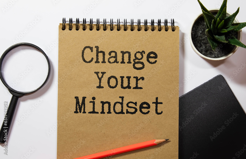 Poster change your mindset. wooden table. torn page from a notebook on two notebooks with text.