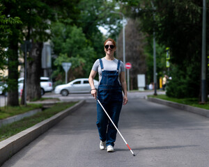 Blind pregnant woman walking down the street with a cane. 
