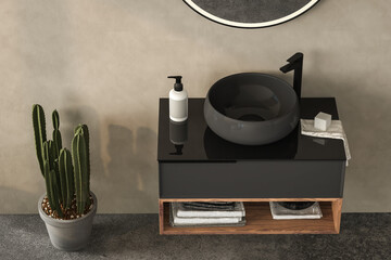 Close up bathroom vanity hanging on beige wall with black sink and oval mirror, towel, plant.
