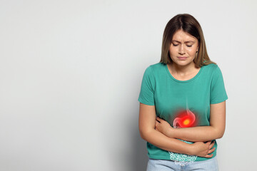 Healthcare service and treatment. Woman suffering from abdominal pain on light grey background....