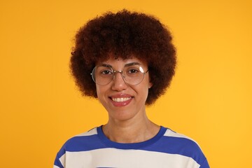 Fototapeta na wymiar Portrait of happy young woman in eyeglasses on orange background