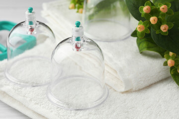 Cupping therapy. Plastic cups, towels and hypericum perforatum berries on table, closeup