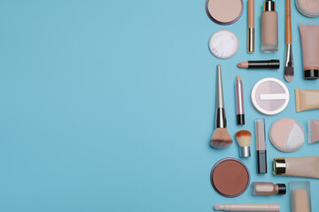 Face powders and other decorative cosmetic products on light blue background, flat lay. Space for text