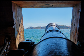 Sea view out of a gunport in hull of the ship over the gun cannon muzzle in on the gun deck of a...