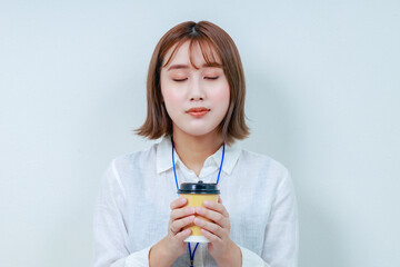 温かい飲み物を両手で持ってホッとする女性