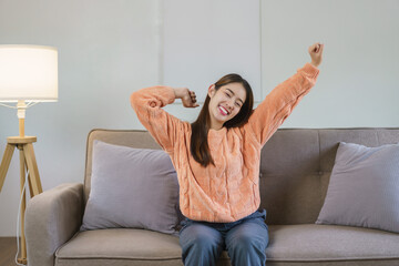 Women raise arms to stretching and exercise while sitting on big sofa to relax in lifestyle at home