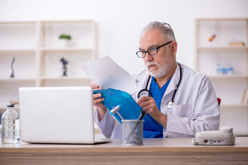 Old male doctor working in the clinic