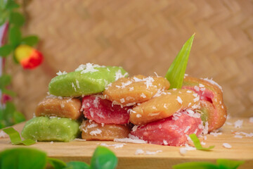 Getuk with three colors. A snack originating from Central Java, Indonesia. Getuk made from mashed cassava and served with grated coconut. Bamboo woven background.