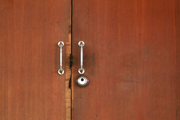 Brown wooden door has a key and a lock and a handle for locking the door to prevent thieves and...