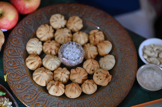 Apples and plate with fried Modak. Silver Bowl with coconut and sugar. White bowls with kishmish and sugar christals. Ganesh Prasad food. Ganesh Chaturthi Ganesh Chaturdashi Ganesh Visarjan 