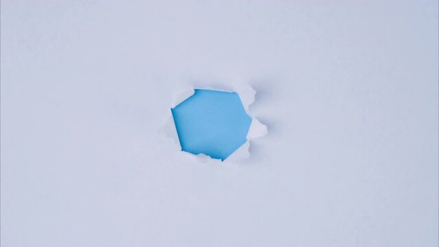 A piece of paper torn from the center revealing a blue background.