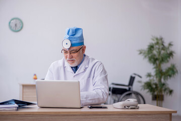 Old male docror otolaryngologist working in the clinic