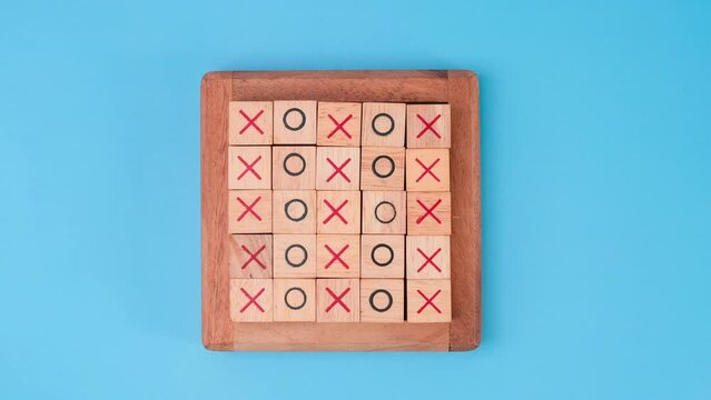 Stop motion animation of wooden game board tic-tac-toe. Turning of the letters X-O and middle one different from each other on blue background.