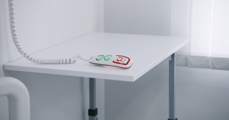Close up shot of remote control with nurse calling system lying on white bedside table in bright...