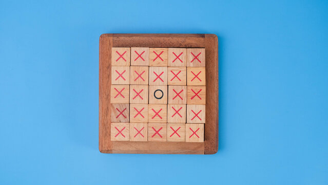 Wooden game board tic-tac-toe. Turning of the letters X-O and middle one different from each other on blue background.