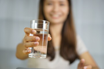 Asian woman working at home holding a glass of water in hand
