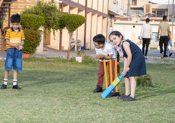 Group of happy Indian kids playing cricket at the summer park.