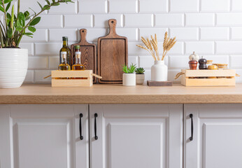 Front view of the kitchen wooden countertop with storage area for oil and various spices in wooden boxes. green plants in pots. Compact storage.