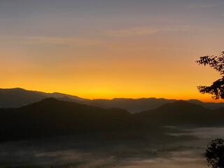 Sunrise behind mountain in the morning with magnificent mist landscape in winter season.