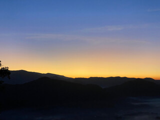 Sunrise behind mountain in the morning with magnificent mist landscape in winter season.