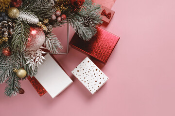 Gifts under decorated Christmas tree brunches. White and red boxes on pink. Copy space banner ready, top view. Festive gritting card with presents