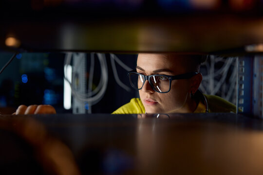 Young woman IT engineer working in datacenter room connecting cables
