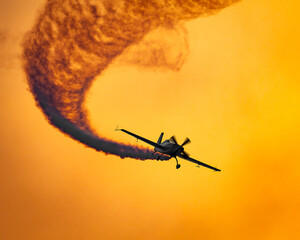 Airshow Extra 300 SC flying at dusk with smoke trail