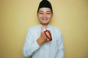 an Indonesian Muslim man of Asian descent wearing Muslim clothes and a black peci, celebrating Eid...
