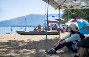 Woman sitting on the crowded Pope Beach. Unrecognizable people playing on the beach. South Lake...