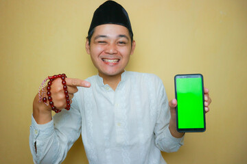 an Indonesian Muslim man of Asian descent wearing Muslim clothes and a black peci, celebrating Eid...