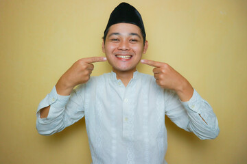 an Indonesian Muslim man of Asian descent wearing Muslim clothes and a black peci, celebrating Eid...