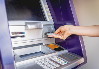 Young woman using the card for withdrawing the cash in the ATM