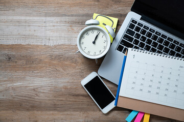 close up of calendar, alarm clock, computer laptop on the wooden table background, planning for...