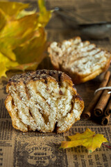 Autumn composition, cinnamon rolls, cross-section of Cinnabons, next to them are cinnamon sticks and yellow leaves on brown craft paper.