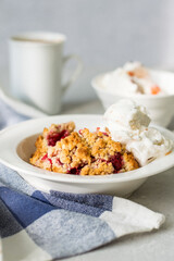 Breakfast, dessert in a bowl - berry crumble with ice cream and a cup of coffee.