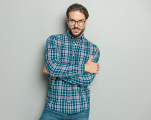 cool casual man with glasses looking forward while crossing arms