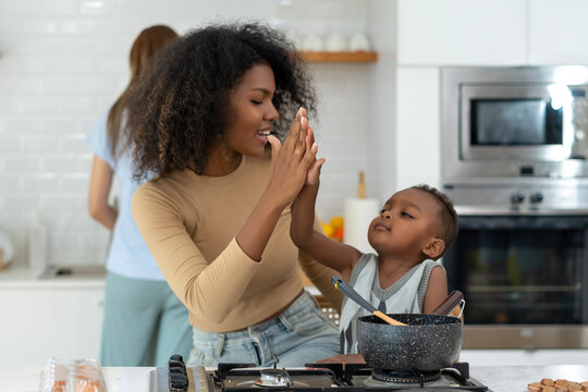 Woman is cooking in home kitchen with cild. She clap hands with the little boy when finished cooking.